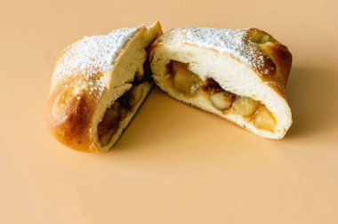 Dilimlenmiş yarım tatlı çörek ve turuncu arka planda elma dolgusu.