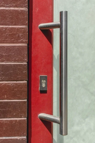 old building exterior plastic door with red frame and white big metal handle
