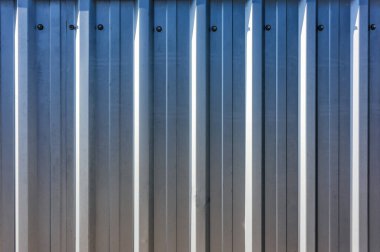 industrial sheet metal profile texture with vertical lines for fence, partially lit sun with rays background
