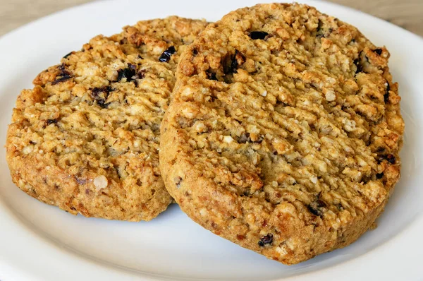 two soft flaky cookies with grains and fruit on a white plate, top view