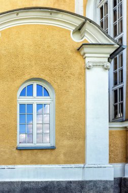 Yellow wall with white column architecture facade with arched window in daylight