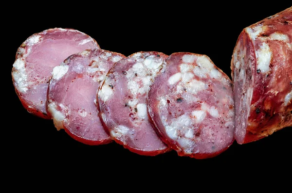 slices of hot smoked ham pork sausage on black background, top view
