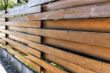Horizontal sections of brown wooden plank garden fence in the distance against sunlight