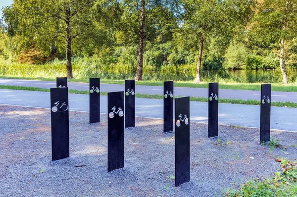 black metal bike racks with a sign in the park next to the bike path