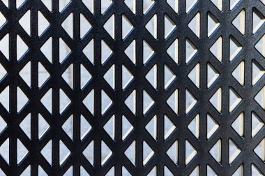 Koyu gri plastik kafeterya koltuğu arka planda gri duvara karşı desenli.