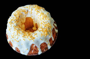 Siyah arka planda beyaz krema ve altın boncuklarla süslenmiş kahverengi kek.