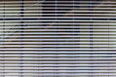 Bina duvarında yatay çizgiler olan büyük bir pencerenin arka plan yakın plan panjurları