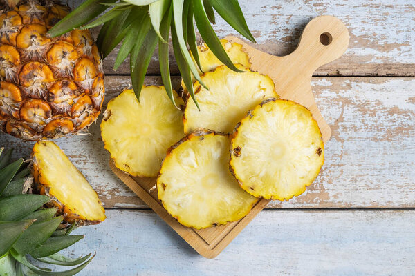 Fresh pineapple fruit sliced on  wooden cutting board