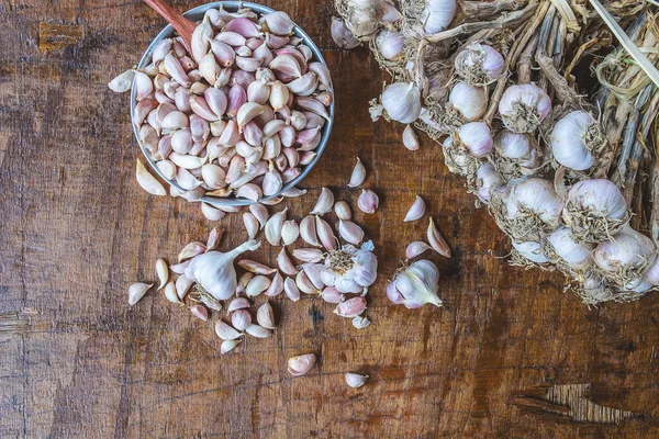 Garlic and garlic cloves in a bowl on a wooden background