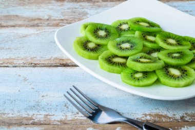 Fresh kiwi fruit in a plate on a wooden table