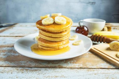 Pancakes topped with honey and bananas on the table
