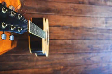 Ahşap zemine yerleştirilmiş akustik gitar.