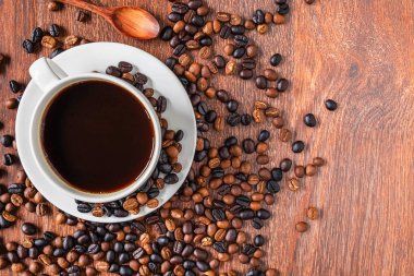 kahve bardakları ve ahşap bir masa üzerinde kahve çekirdekleri