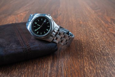 Stainless steel watch and purse on a wooden background