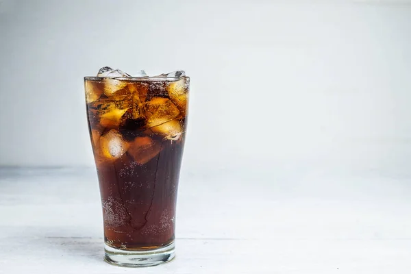 Cola soda in a glass on a white table
