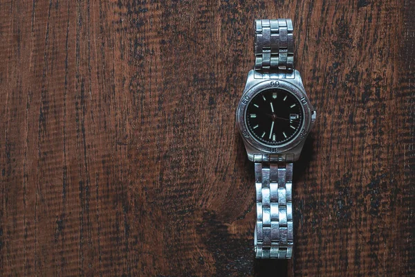 Stainless steel watch on wooden background