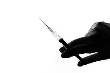 Doktorun elinde beyaz eldivenli şırınga var..