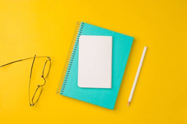 Boş defter sarı masa, üst görünüm, düz yatak için hazır..