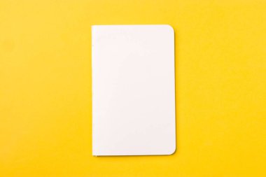 Boş defter sarı masa, üst görünüm, düz yatak için hazır..