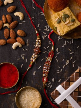 Raksha Bandhan arka planda zarif bir Rakhi ve pirinç taneleri koyu dokulu arka planda.