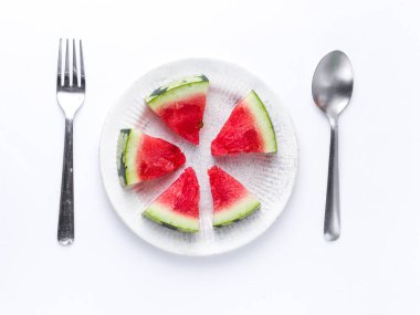 Beyaz tabakta dilimlenmiş karpuz kaşık ve çatal desenli beyaz arka planlı fotoğraf..