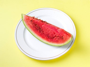 Beyaz tabakta dilimlenmiş karpuz kaşık ve çatal desenli beyaz arka planlı fotoğraf..