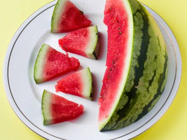 Beyaz tabakta dilimlenmiş karpuz kaşık ve çatal desenli beyaz arka planlı fotoğraf..