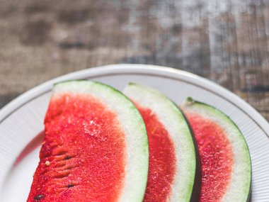 Beyaz tabakta dilimlenmiş karpuz kaşık ve çatal desenli beyaz arka planlı fotoğraf..