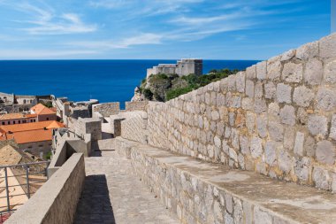 Fort Lovrijenac rises above the city wall as the path slopes downward - Old Town Dubrovnik