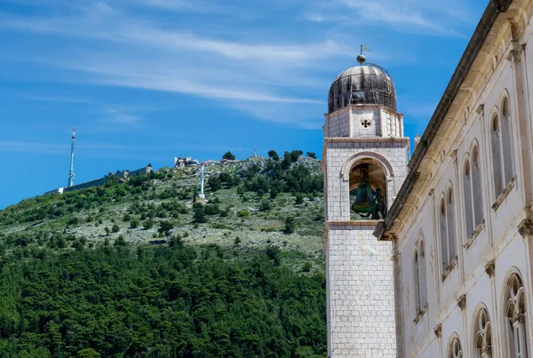 Mt. Srd towers over the Old Town of Dubrovnik as seen against the landmark Bell Tower