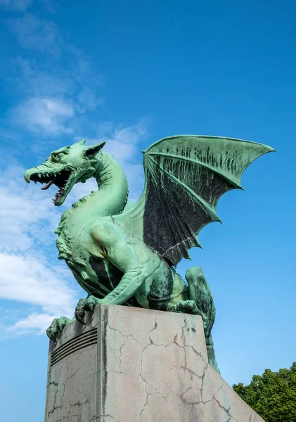 Isolated against wispy clouds and blue sky, the Dragon statue stands guard over Ljubljana
