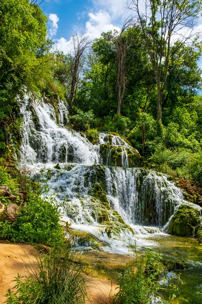 Blue sky and clouds frame a bright cascading waterfall at Krka National Park Croatia