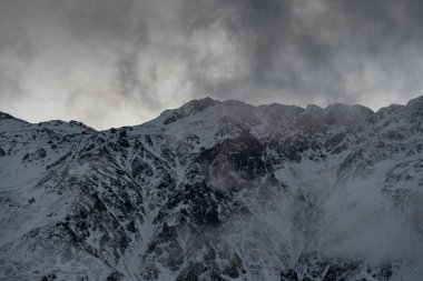 Güneşin doğuşundaki güzel kış dağları manzarası. Yoğun kar sisli dağları kapladı. Georgia, Kazbegi.