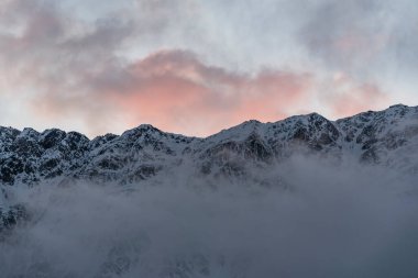 Güneşin doğuşundaki güzel kış dağları manzarası. Yoğun kar sisli dağları kapladı. Georgia, Kazbegi.