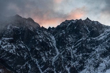 Güneşin doğuşundaki güzel kış dağları manzarası. Yoğun kar sisli dağları kapladı. Georgia, Kazbegi.