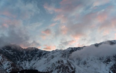 Güneşin doğuşundaki güzel kış dağları manzarası. Yoğun kar sisli dağları kapladı. Georgia, Kazbegi.
