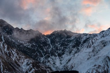 Güneşin doğuşundaki güzel kış dağları manzarası. Yoğun kar sisli dağları kapladı. Georgia, Kazbegi.