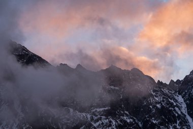 Güneşin doğuşundaki güzel kış dağları manzarası. Yoğun kar sisli dağları kapladı. Georgia, Kazbegi.