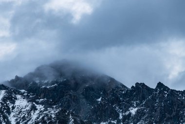 Güneşin doğuşundaki güzel kış dağları manzarası. Bulutlarda yüksek kar örtülü dağlar. Georgia, Kazbegi.