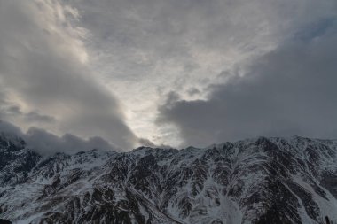 Güneşin doğuşundaki güzel kış dağları manzarası. Yoğun kar sisli dağları kapladı. Georgia, Kazbegi.