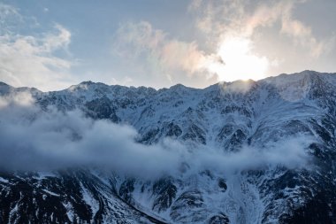 Güneşin doğuşundaki güzel kış dağları manzarası. Yoğun kar sisli dağları kapladı. Georgia, Kazbegi.