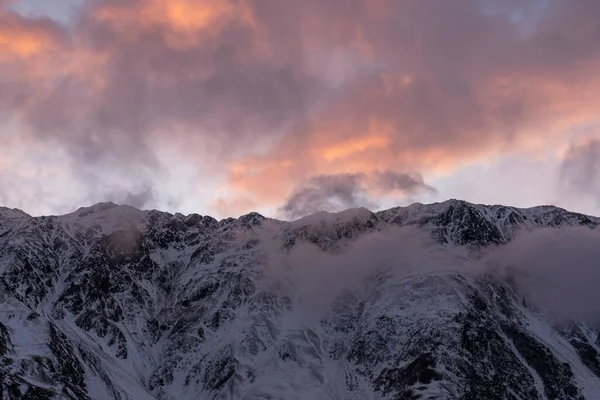 Güneşin doğuşundaki güzel kış dağları manzarası. Yoğun kar sisli dağları kapladı. Georgia, Kazbegi.
