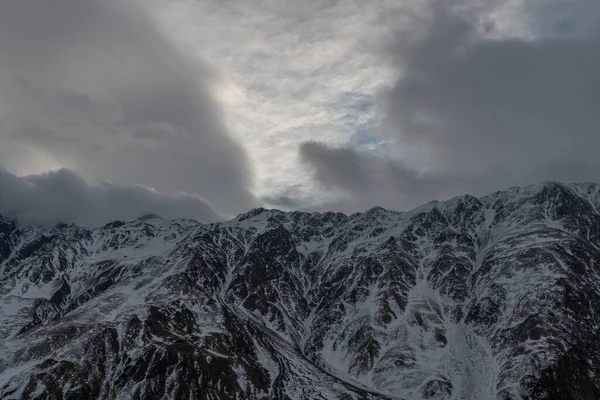 Güneşin doğuşundaki güzel kış dağları manzarası. Yoğun kar sisli dağları kapladı. Georgia, Kazbegi.