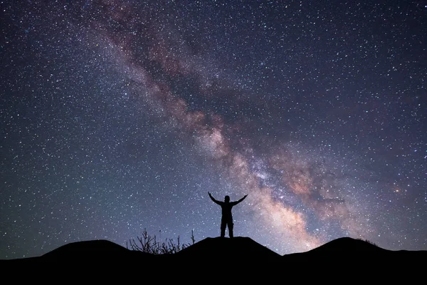 星空の丘の上のシルエットの旅行者 彼の後ろの明るい天の川銀河 ストック写真
