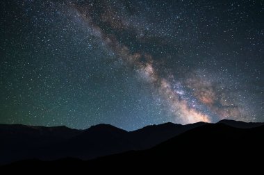 Gece gökyüzünde ve tepelerin siluetinde güzel parlak Samanyolu Galaksisi. Astronomik arkaplan.