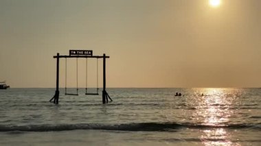 Plaj sallanıyor ve okyanus dalgalarını izliyor. Okyanus sahilinde kaygısız bir yaz anı.