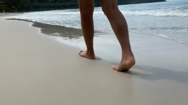 Kumlu sahilde deniz dalgaları boyunca yürüyorum. Güzel kadın deniz kıyısında sörf yapıyor..