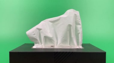 a person's hand pull out a piece of tissue from tissue paper box isolated on green background.