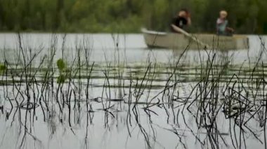 two fishermen are fishing on a boat in the forest