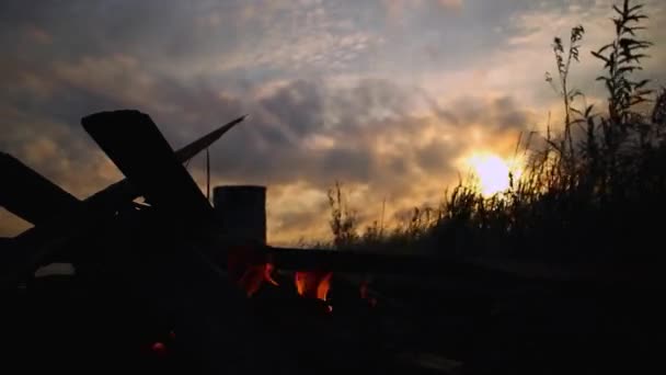 Fuego ardiente en la noche contra el telón de fondo de la puesta del sol, protector de pantalla — Vídeo de stock